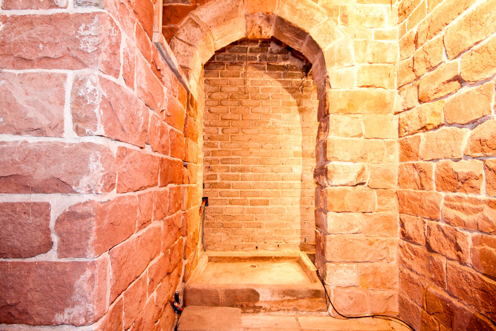 Photograph of a stone arched doorway with a shower drain inside